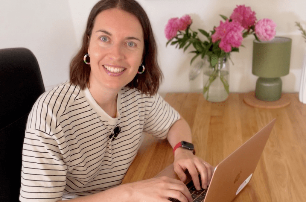 a woman sitting at a desk and typing on a laptop